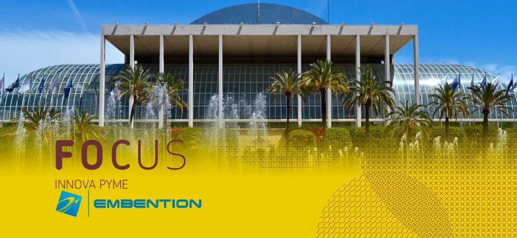 FOCUS Innova PYME 2015 event banner, with a modern glass building and fountains in the background, featuring Embention logo