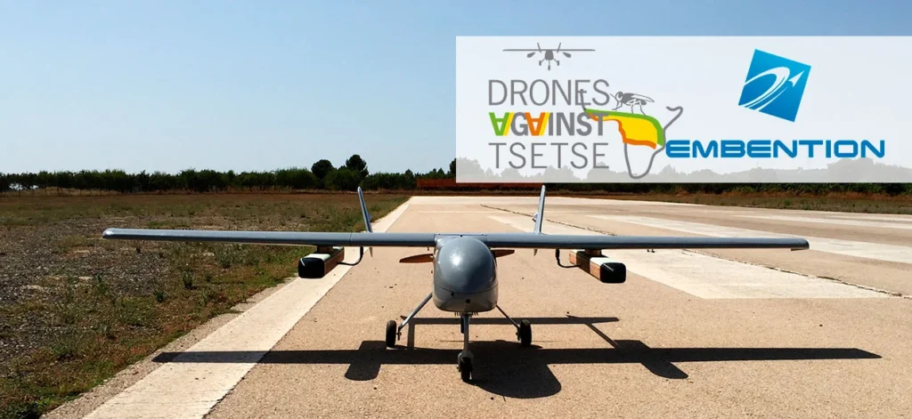 Drone ready for takeoff on a runway with company logos and a clear sky.