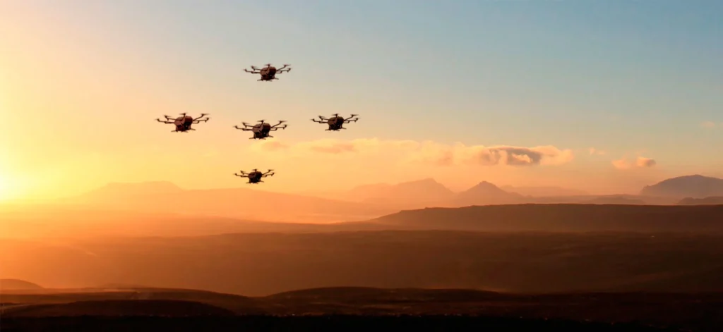 Several drones flying in formation against a sunset backdrop, illustrating the concept of UAV formation flight and its applications in various missions.