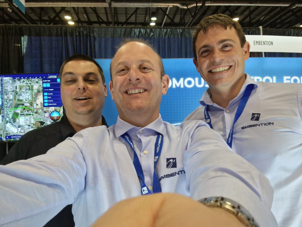 Three Embention's employees taking a selfie wearing lanyards