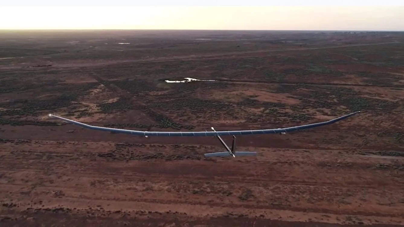 phasa-35-bae-systems-hibrido-dron-2 Aerial view of a high-altitude drone flying over a remote, arid landscape at sunset.