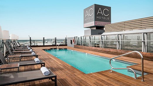 AC AC Hotels rooftop pool with lounge chairs and city view.