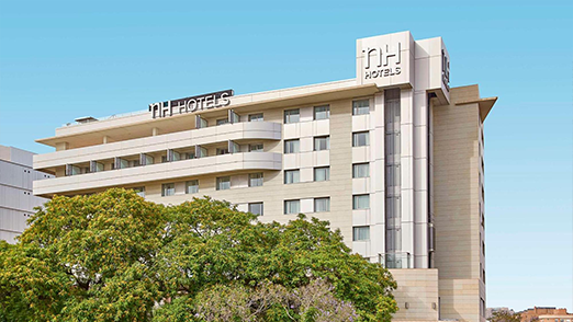 NH NH Hotels building surrounded by greenery.