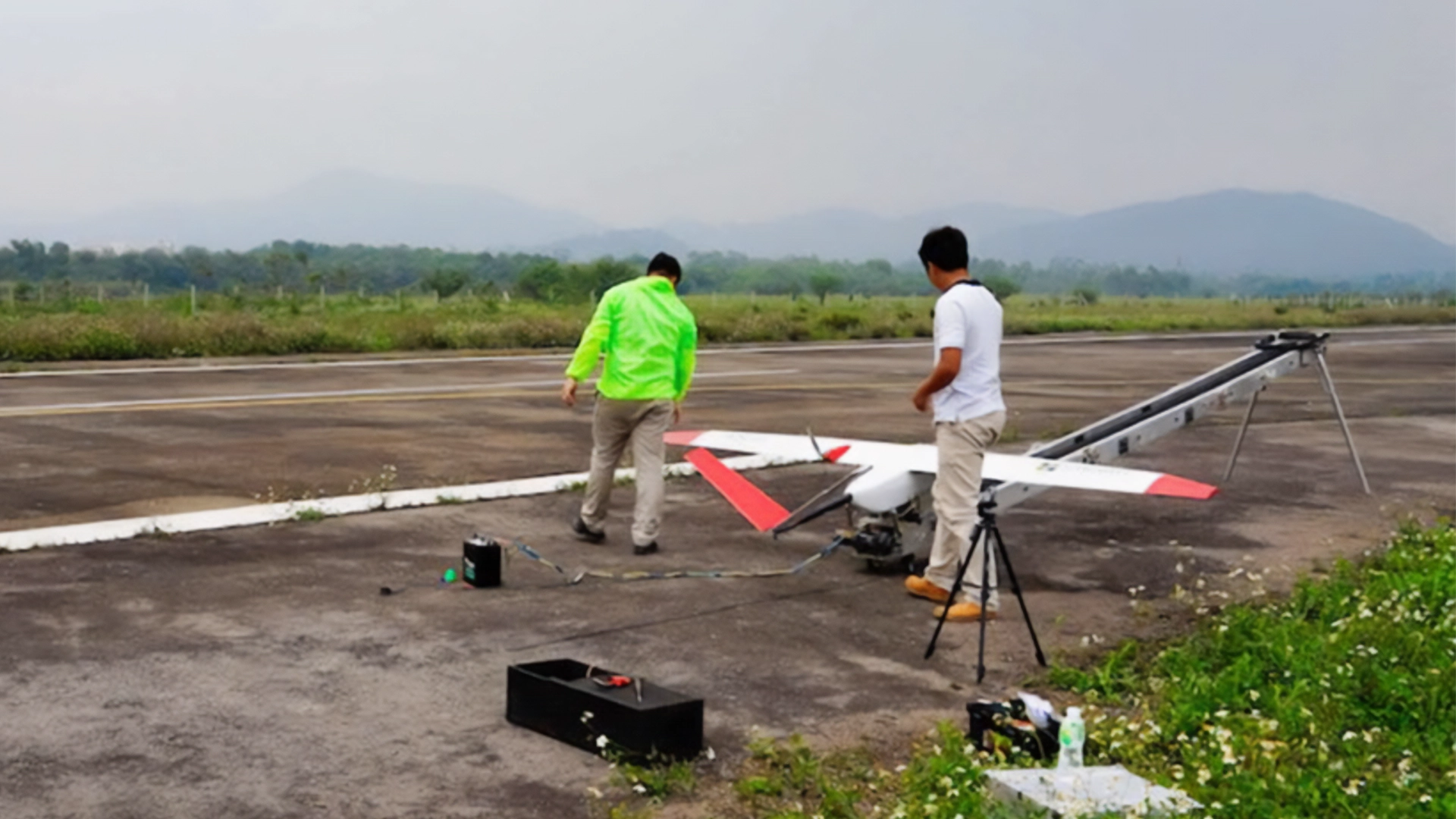 Insight Robotics - AS-III UAS 5 Two technicians preparing the AS-III UAS for launch using a catapult on a runway, with a green landscape in the background.
